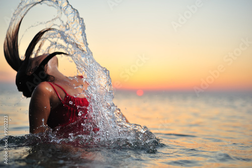 Young girl in red dress breaking out from sea