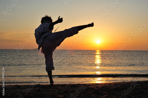 Young boy in karate uniform training at sunset