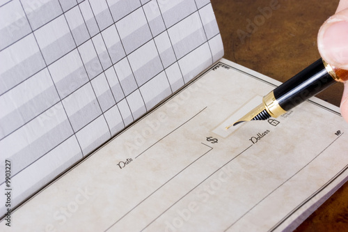 Hand holding pen writing in chequebook , paying the bills