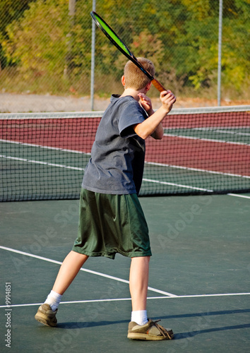 A teenage boy playing tennis, shwing his forehand