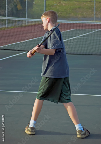 A teenage boy playing tennis - showing his backhand
