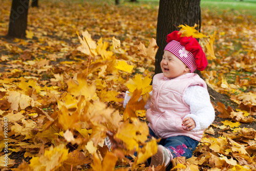 Laughing toddler and falling golden leaves