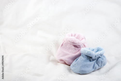 A pair of pink and blue baby shoes on a white background. © Julien BASTIDE