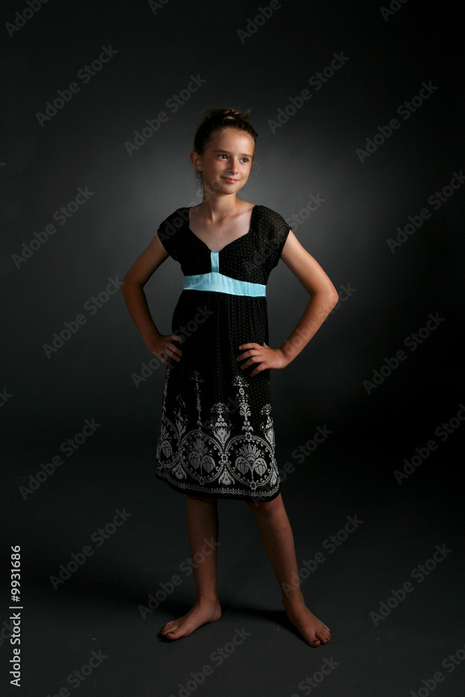 cute girl standing in black dress with blue sash