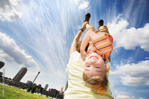 Happy young boy hanging upside down on mother's back photo