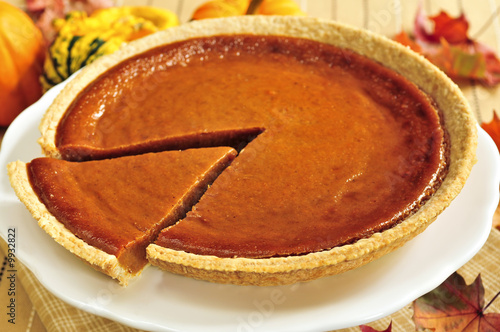 Whole pumpkin pie with a slice cut out