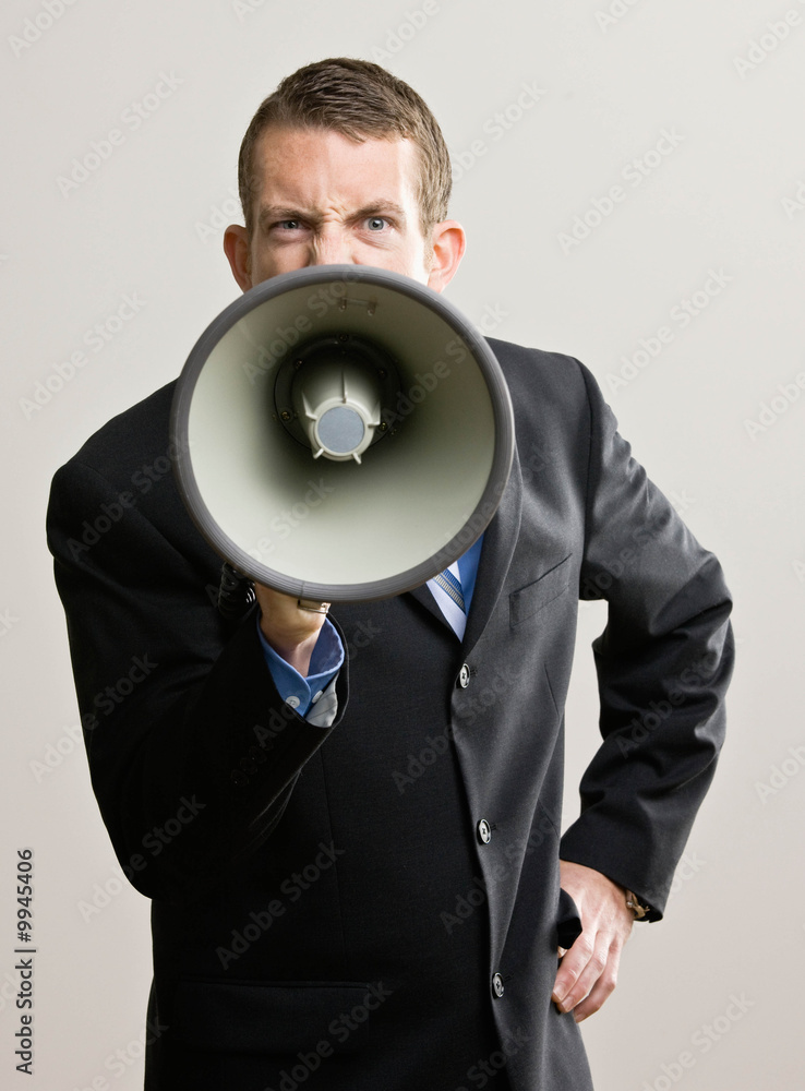 Angry businessman shouting instructions into megaphone Angry businessman shouting instructions into megaphone