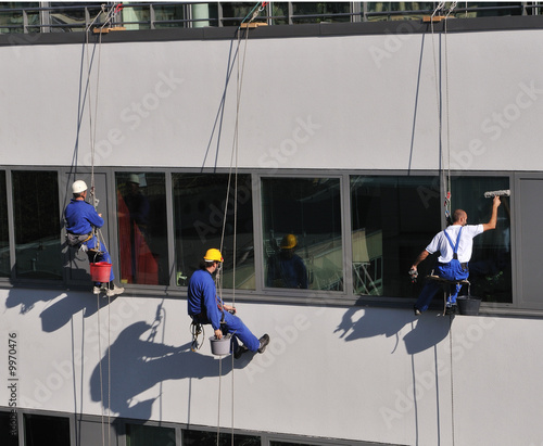 Three men cleaning windows of office building..