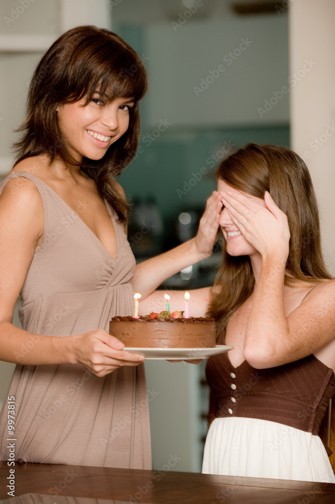 Two young attractive women celebrating a birthday with cake