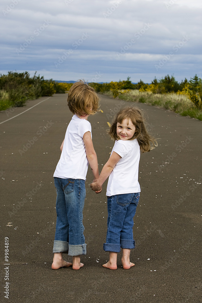 Barefoot kids walking down the road holding hands Barefoot kids walking down the road holding hands