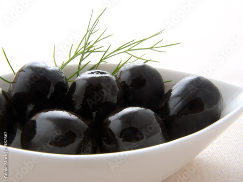 White bowl full of black olives with dill bunch adition photo