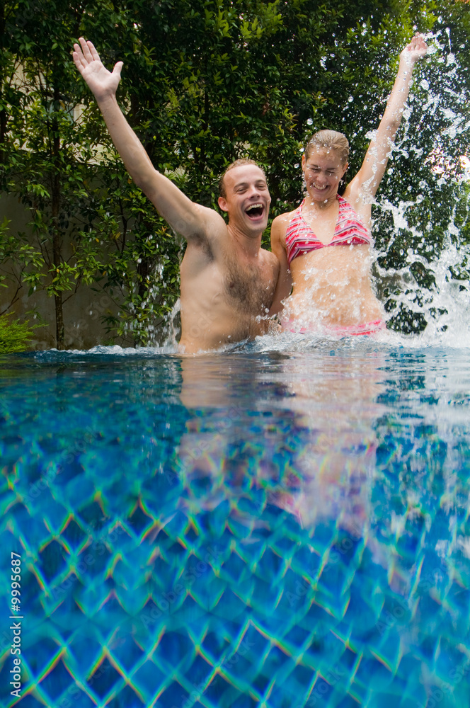 A couple jumping out of swimming pool
