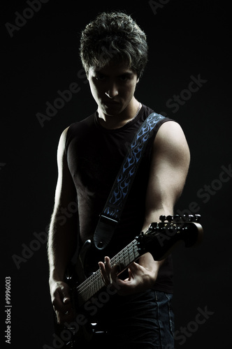 silhouette of man with guitar over black background