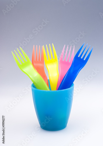 Colored forks in blue tumbler with continous background