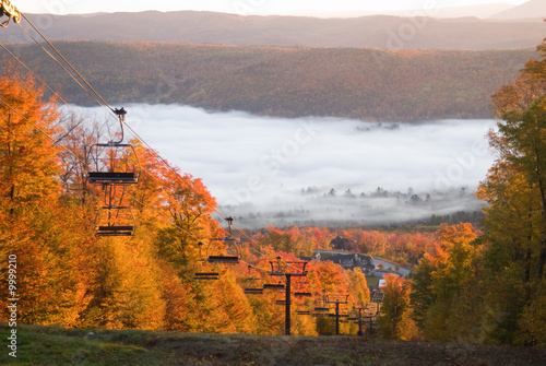 Chairlift on a fall mountain slope with morning mist