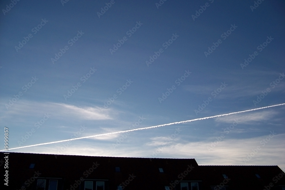 Fototapeta premium Trace from the plane in the evening sky over a house roof