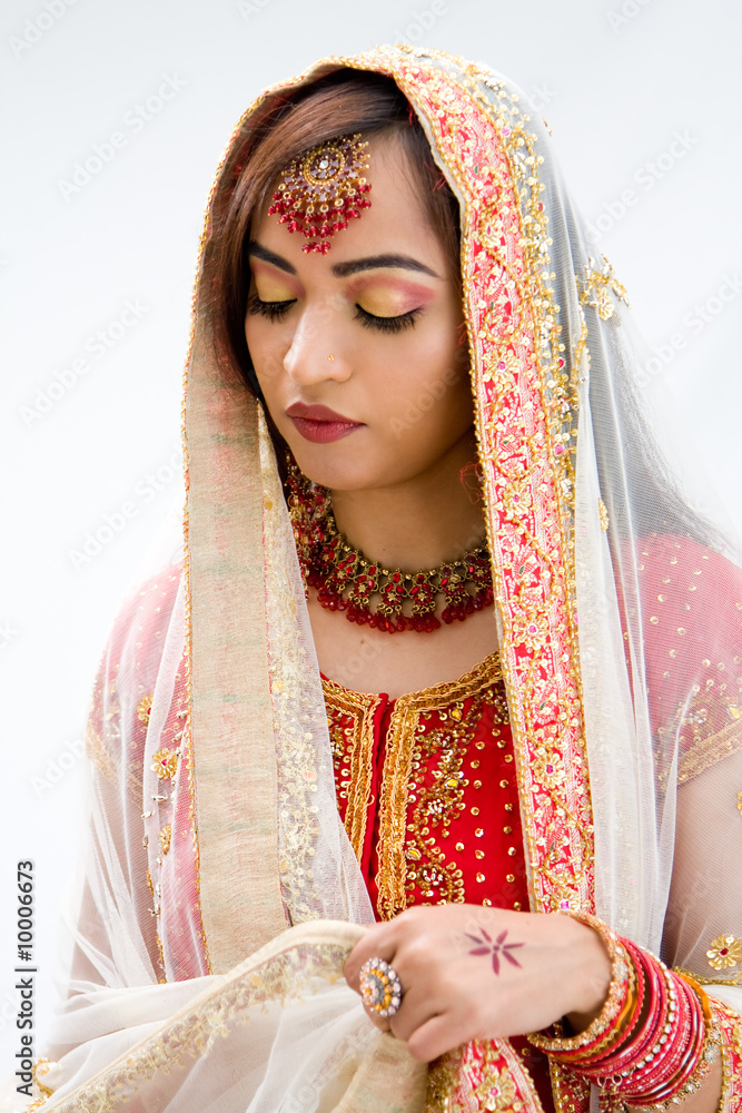 Fotografie Elegant Bengali bride arranging veil looking down, isolated