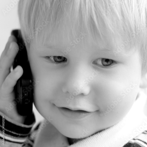 The child smiles and speaks on the phone