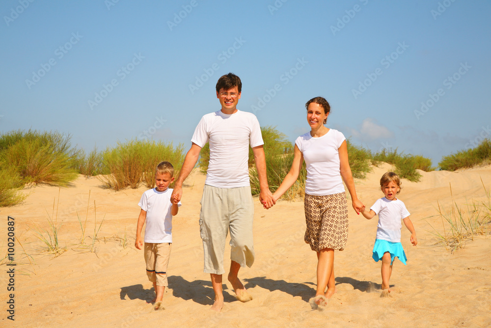 Family of four walk on sand Family of four walk on sand