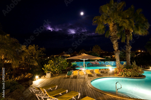 swimmingpool at night with thunder in the back