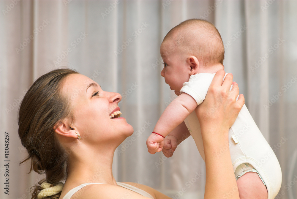 Young mother is playing with her little baby