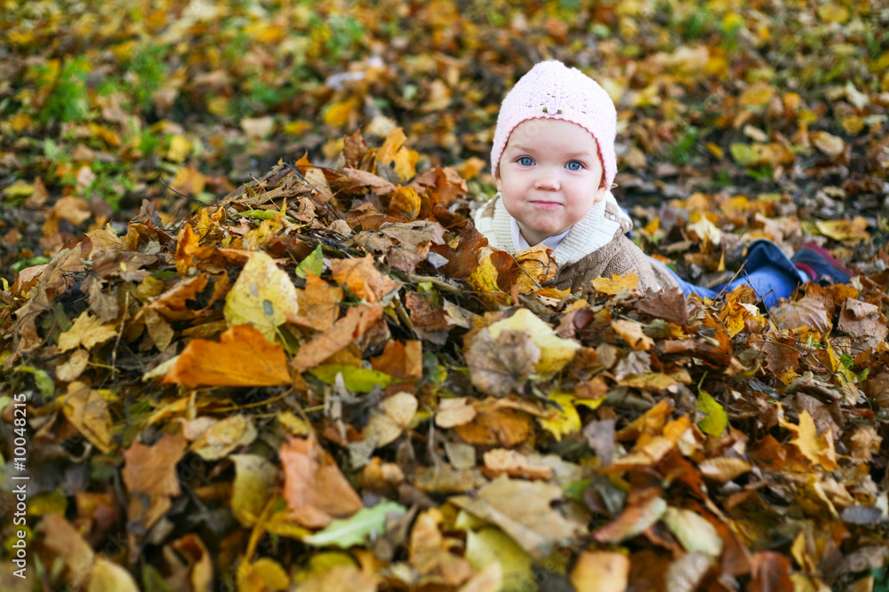 A little child playing in yellow maple leaves A little child playing in yellow maple leaves