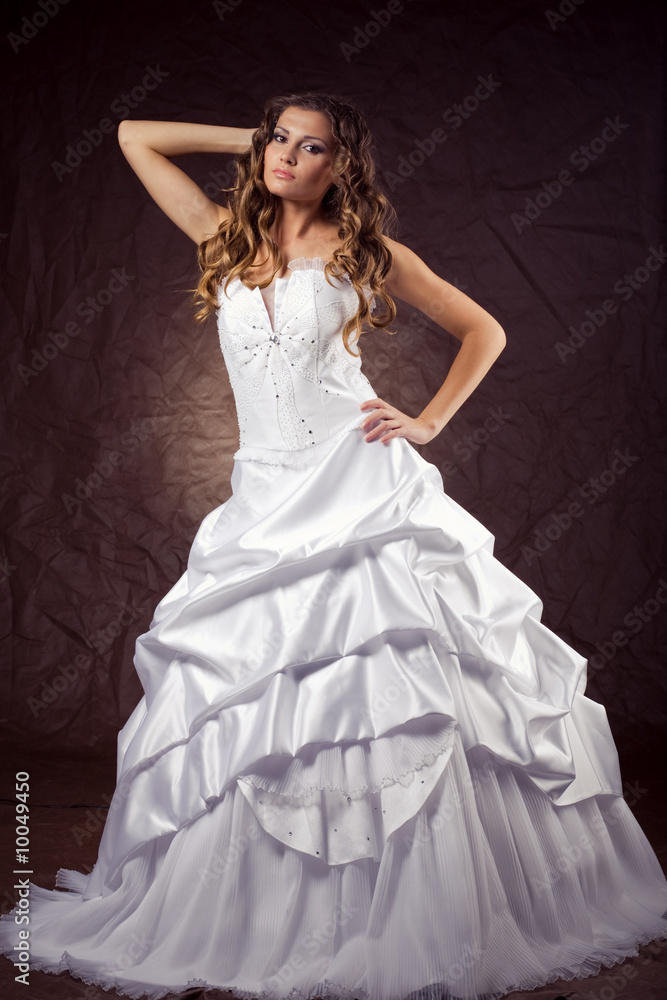 Fashion model wearing wedding dress at brown studio background Fashion model wearing wedding dress at brown studio background
