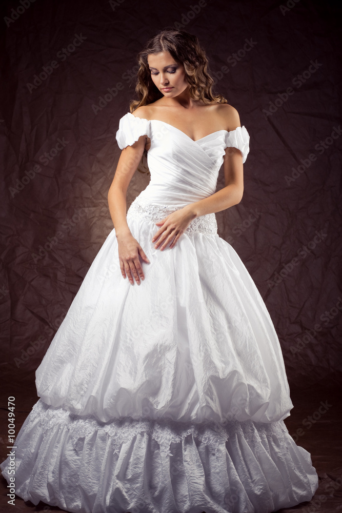Fashion model wearing wedding dress at brown studio background Fashion model wearing wedding dress at brown studio background