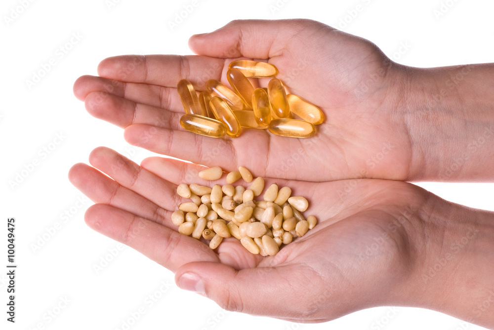 Hands weighting pine nuts and fish oil capsules Hands weighting pine nuts and fish oil capsules
