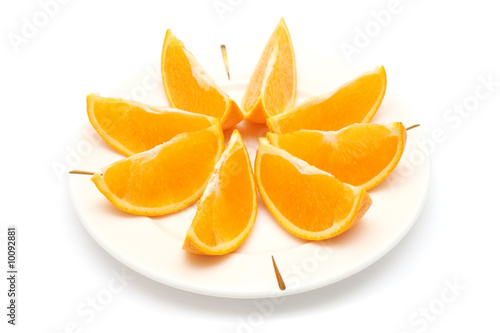 Orange cut into eight pieces on white plate.