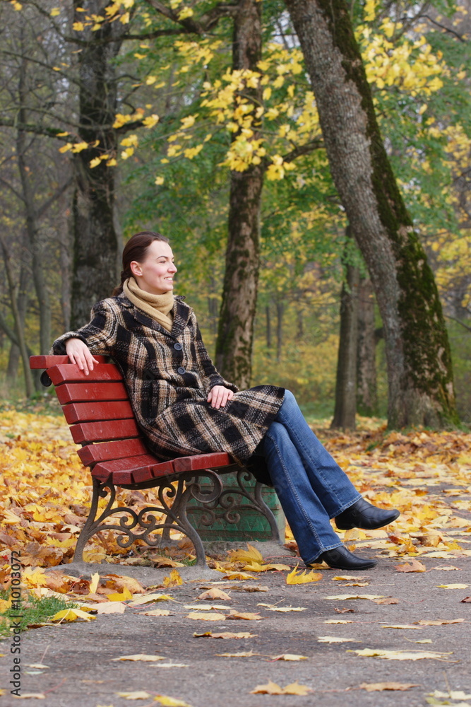 Young woman sitting on a bench in an autumn park