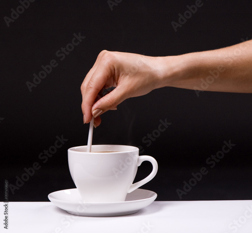 Quadro em tela woman stir sugar in cup of coffee over black background