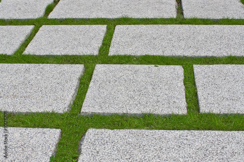 Path from the granite plates on a green grass