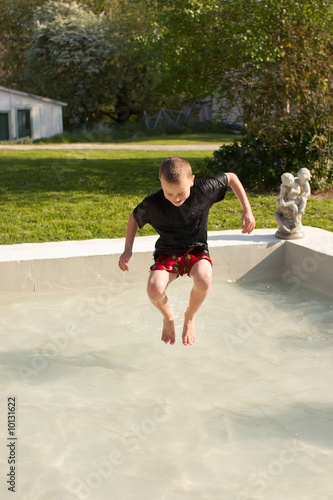 A young male boy splashes in a pool on a warm spring day photo