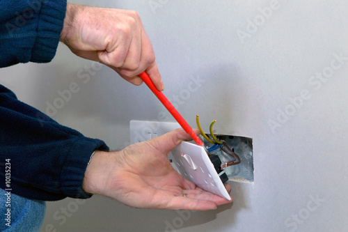 The hands of an electrician installing a power socket photo