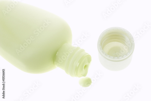 Dripping cosmetic lotion on white background