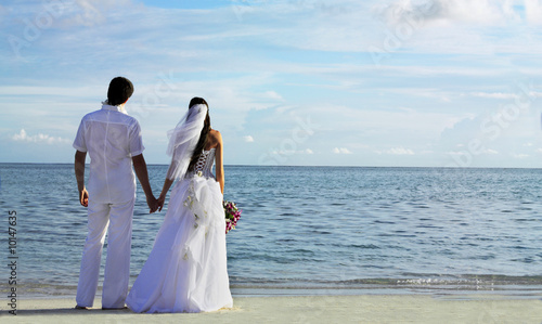 bride and groom standing hands at the beach