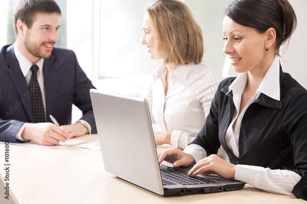 operates a laptop and her colleagues hold discussions operates a laptop and her colleagues hold discussions