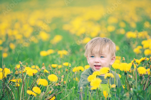 Cute small boy in green grass - he smiles and has fun