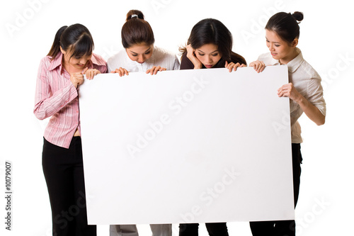 four girls lloking at a white sign photo
