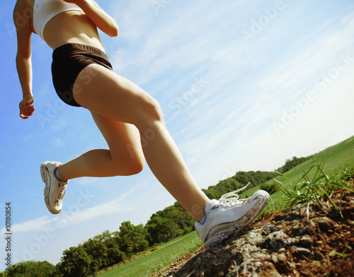 Beautiful woman runner in front of blue sky, low angle. photo