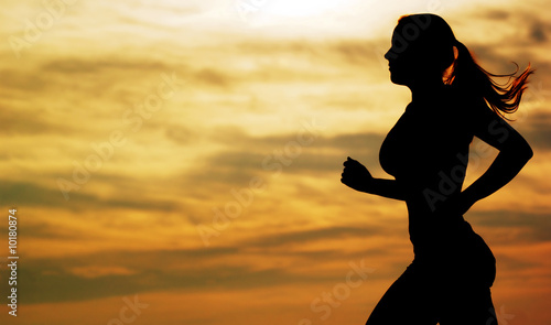 Beautiful young woman running in front of a sunset.