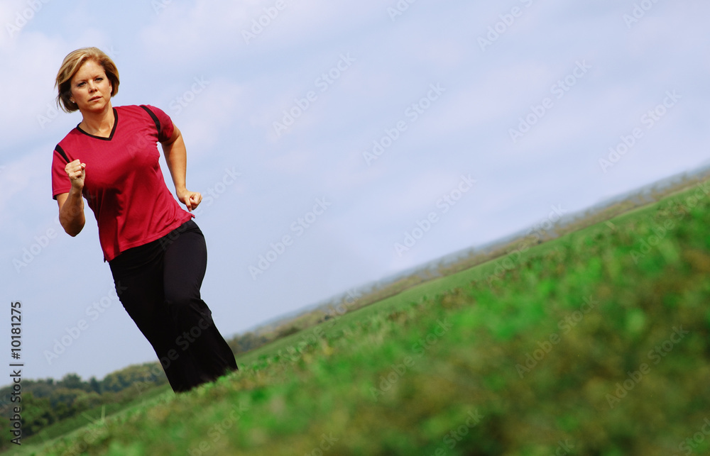 Mature woman jogging in a big summer field. Mature woman jogging in a big summer field.