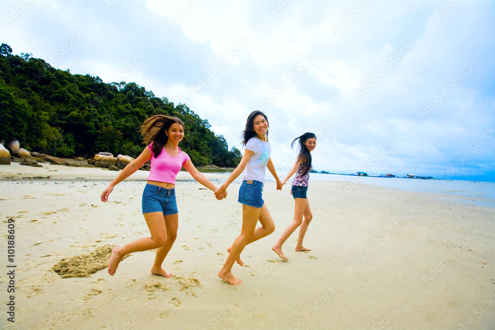 group of asian girls holding hands having fun at the beach