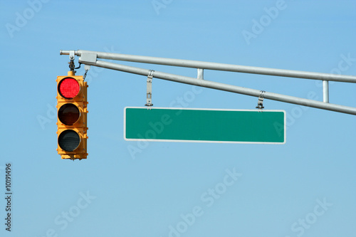 Red traffic signal light with sign on blue sky