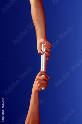 hands passing the batton against blue sky