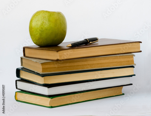 Pile of books, pen,  and apple isolated on white background photo