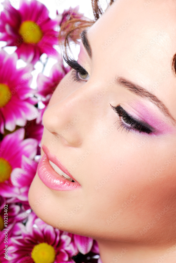 Face of a young beautiful woman. Flowers on the background Face of a young beautiful woman. Flowers on the background