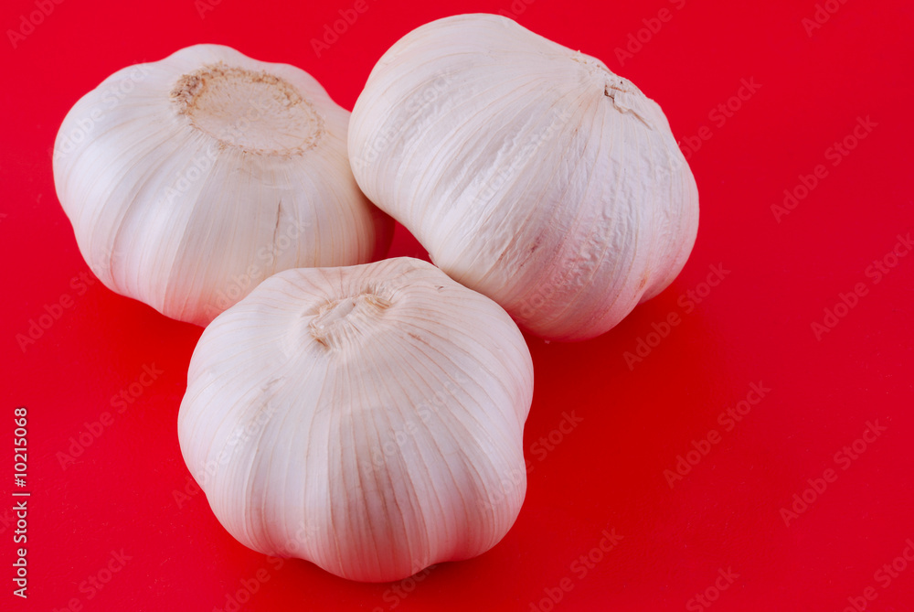 Three garlics on red background Three garlics on red background