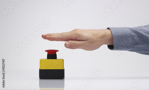 a hand is pressing the red emergency button